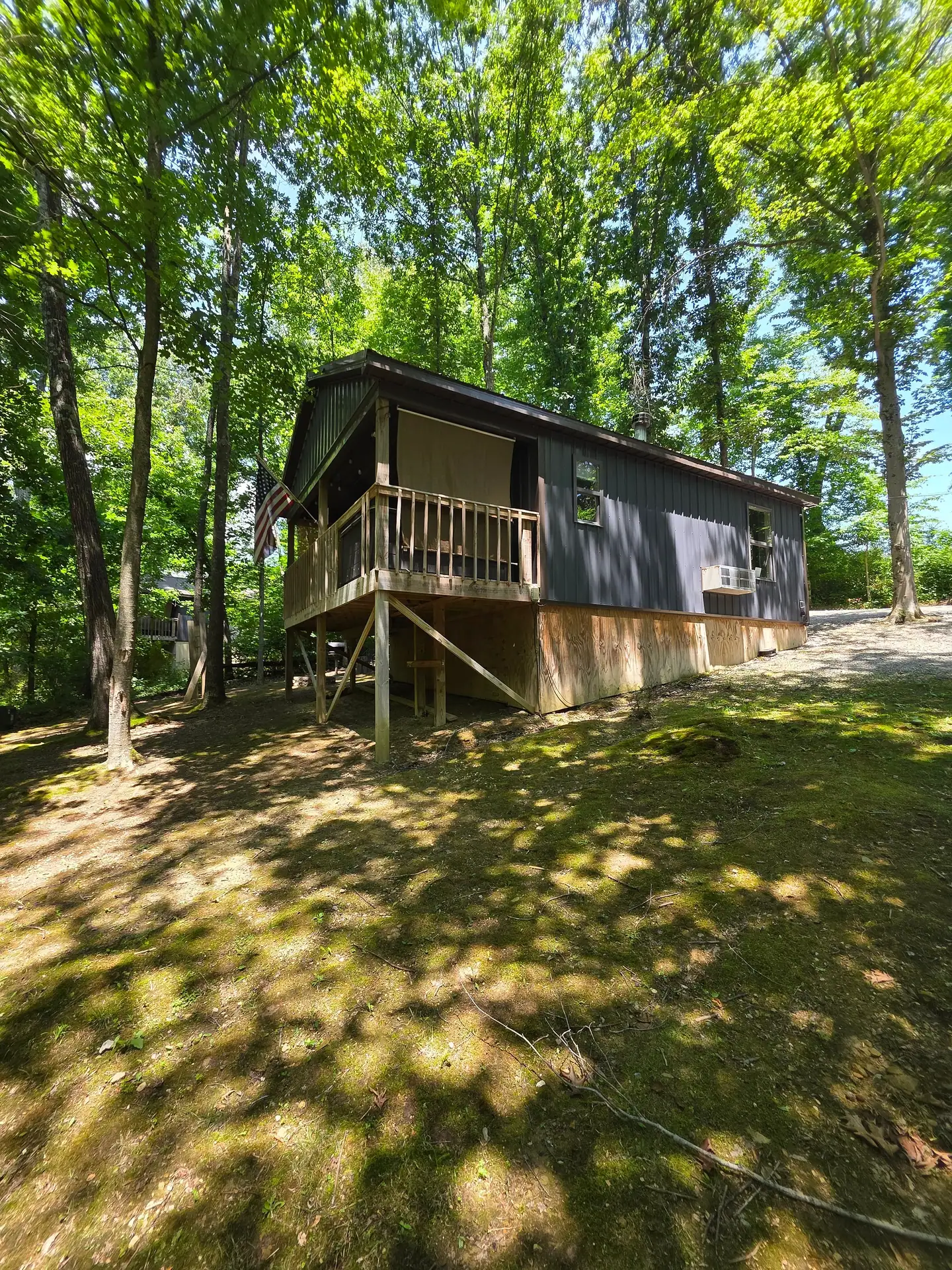 Back of the cabin with raised covered deck seen from the mossy yard at Owl's Tale cabin