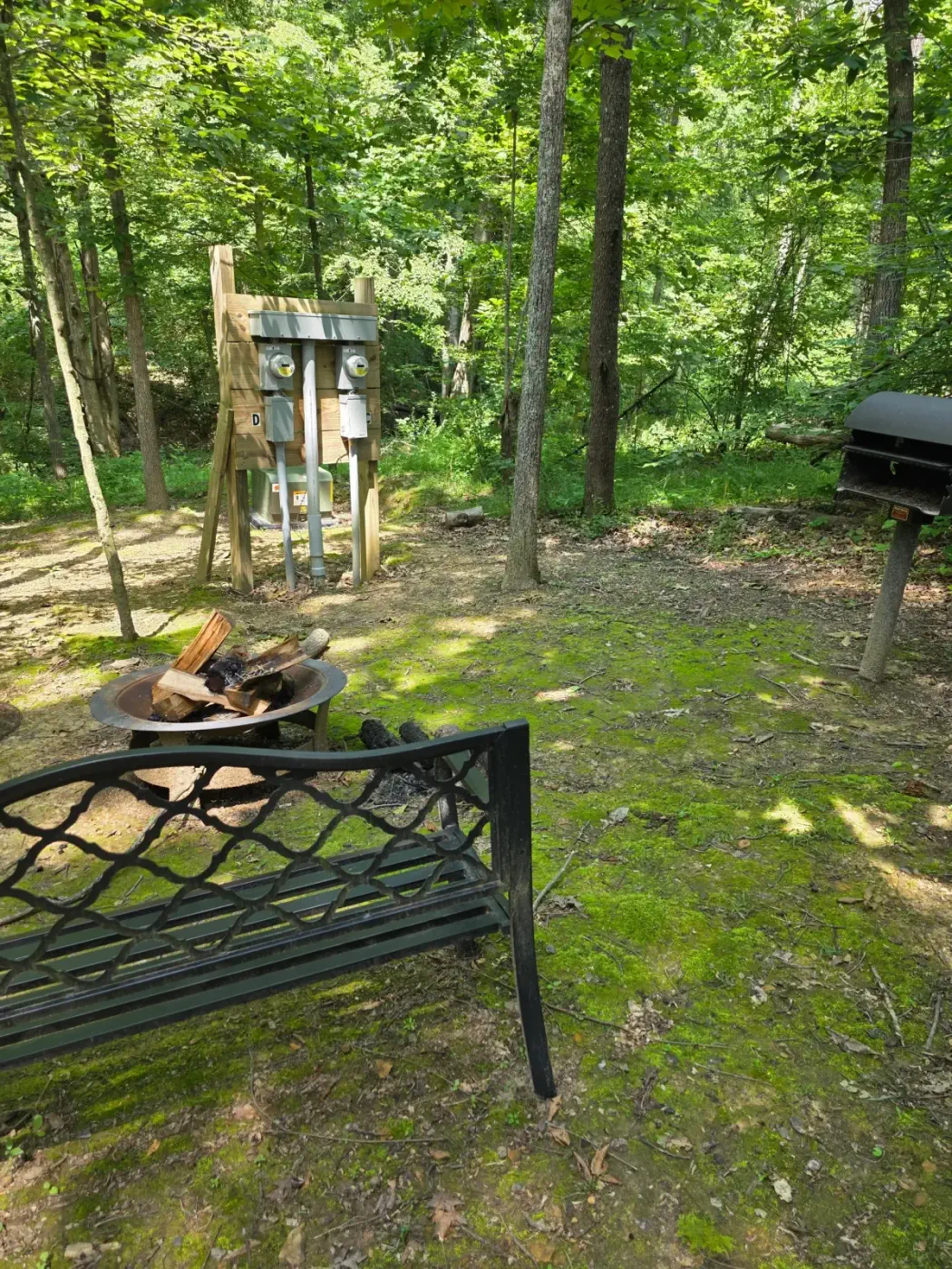 Fire pit with metal bench seating in the shaded yard at Owl's Tale cabin