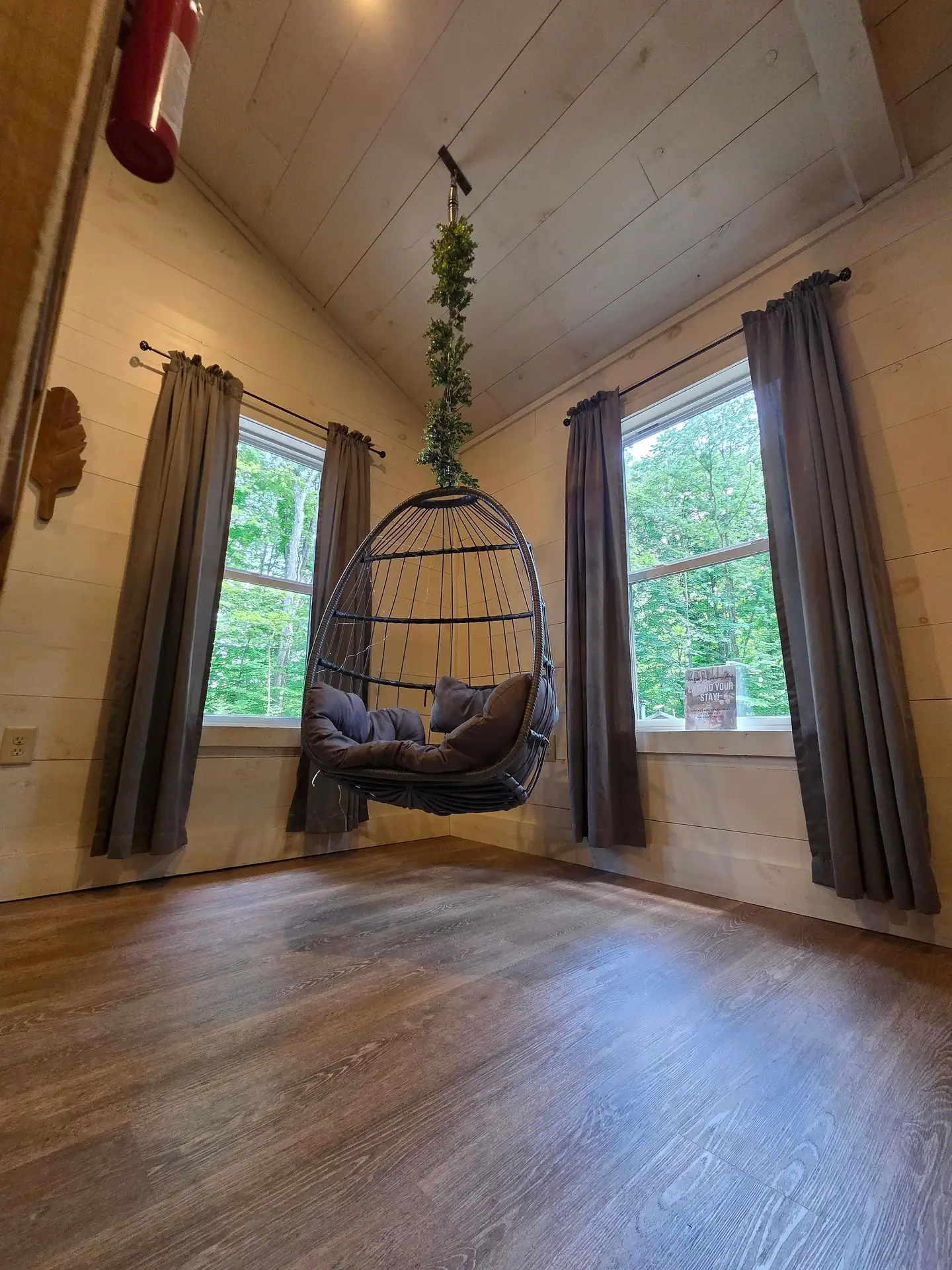 Hanging egg chair between two windows with gray curtains at Owl's Tale cabin