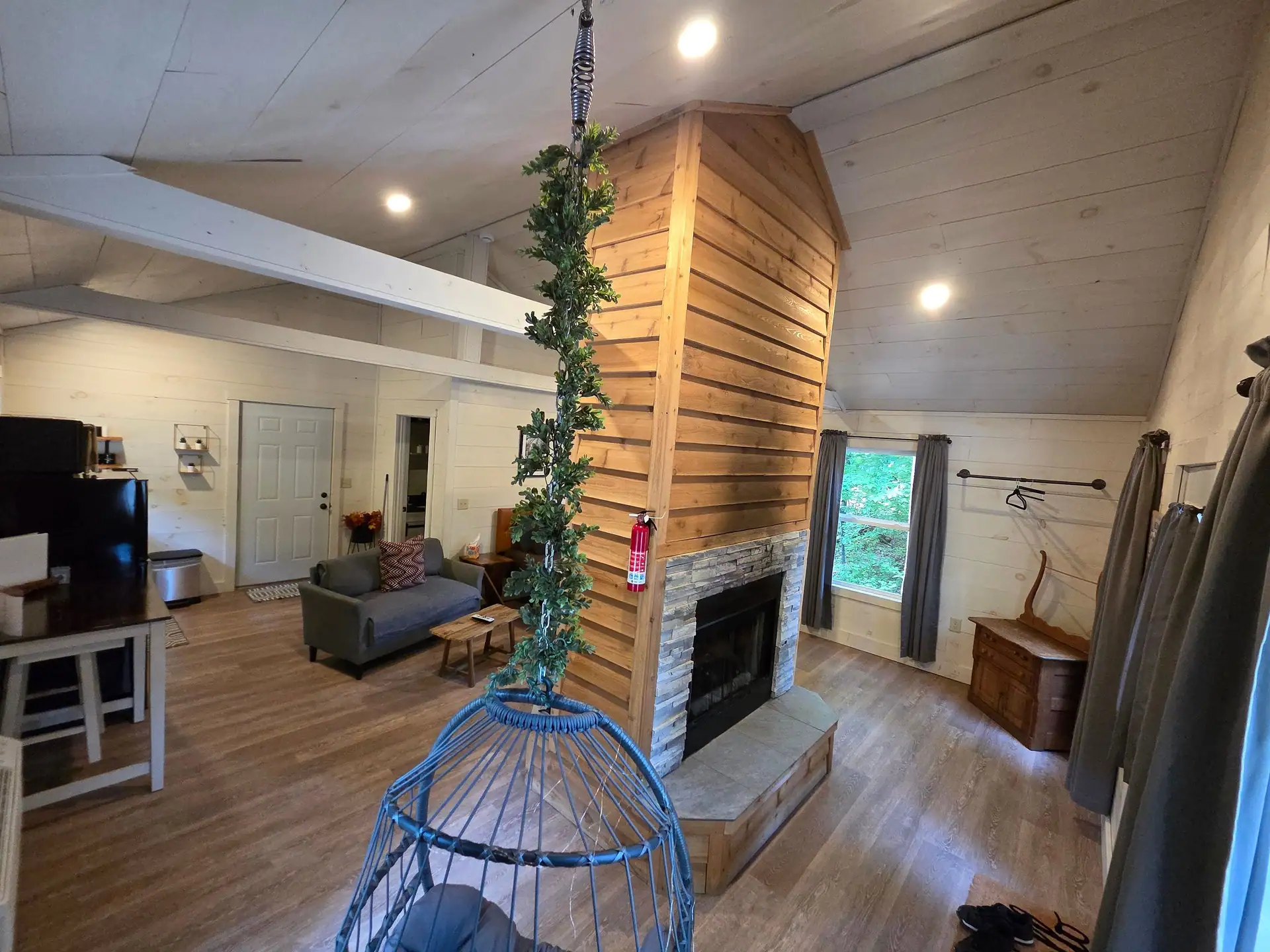 Interior view from the hanging egg chair toward the fireplace and living area at Owl's Tale cabin