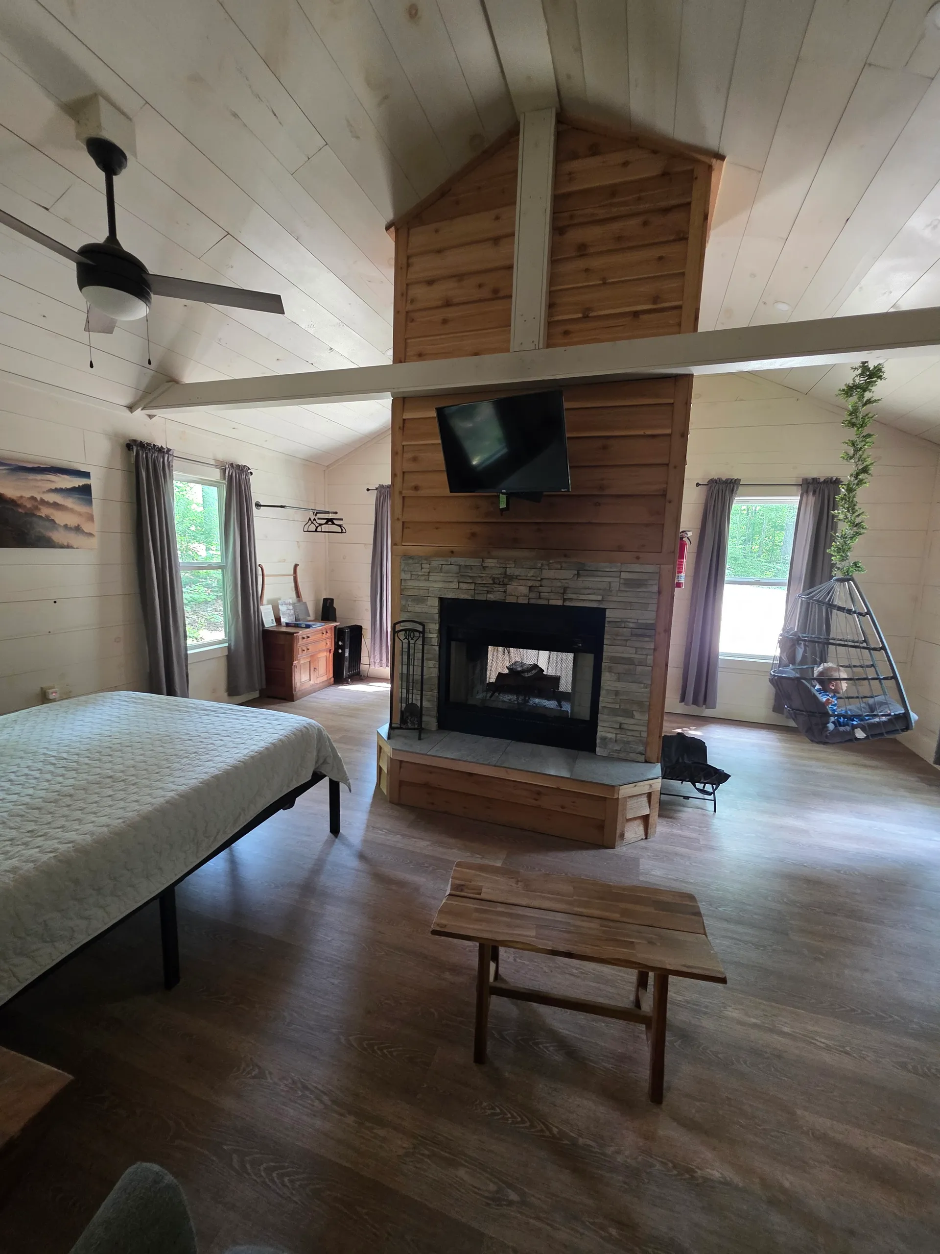 Wide-angle view of the full interior showing bedroom, fireplace, and living area at Owl's Tale cabin