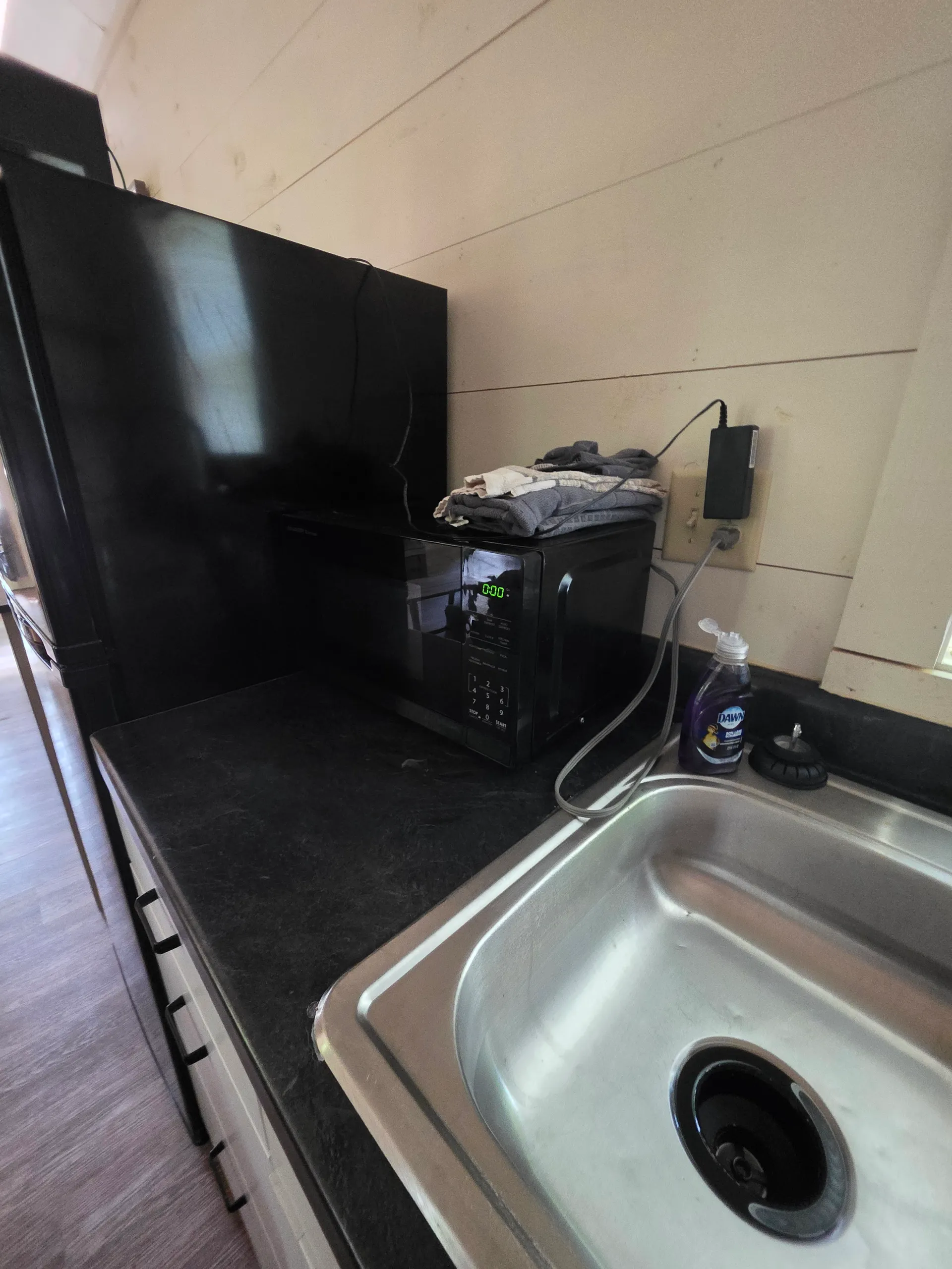Kitchenette counter with microwave, sink, and dish supplies at Owl's Tale cabin