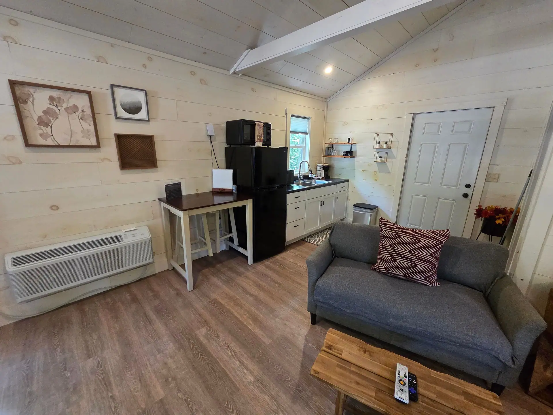 Living area with gray sofa, coffee table, and kitchenette at Owl's Tale cabin