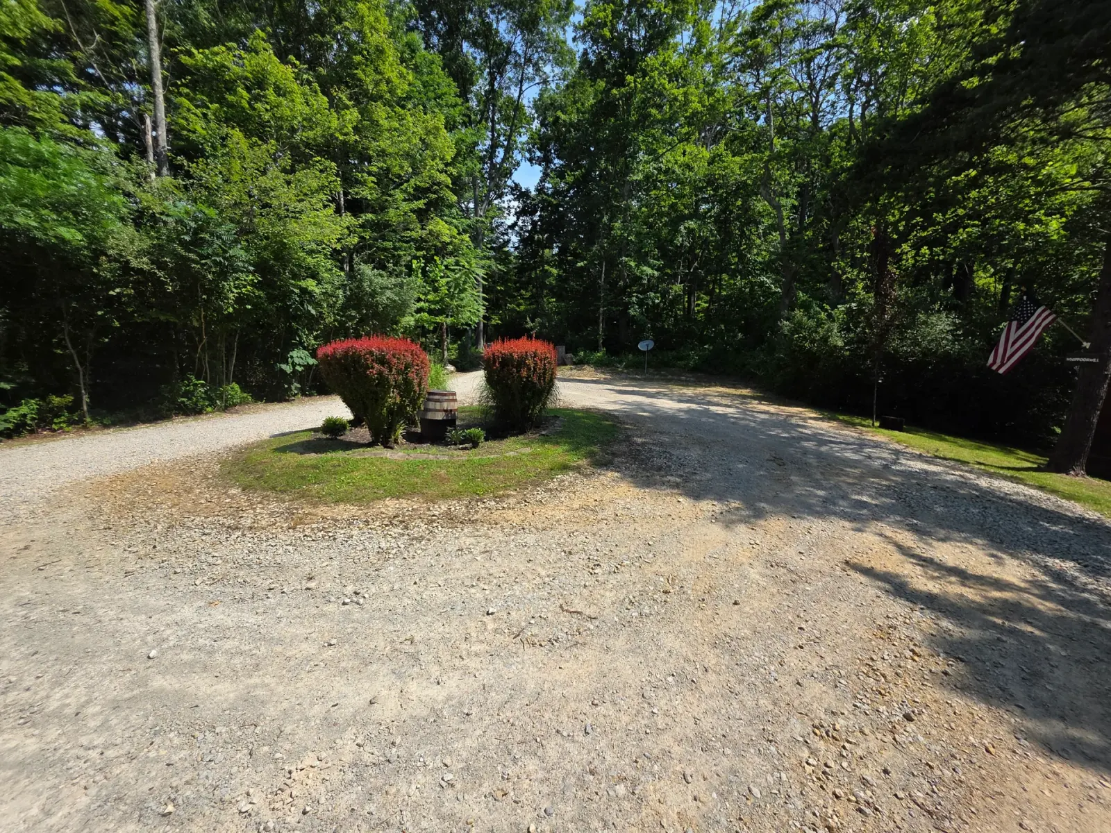 Spacious gravel driveway and entrance to Settlers Roost cabin with flowering shrubs and mature trees in Hocking Hills
