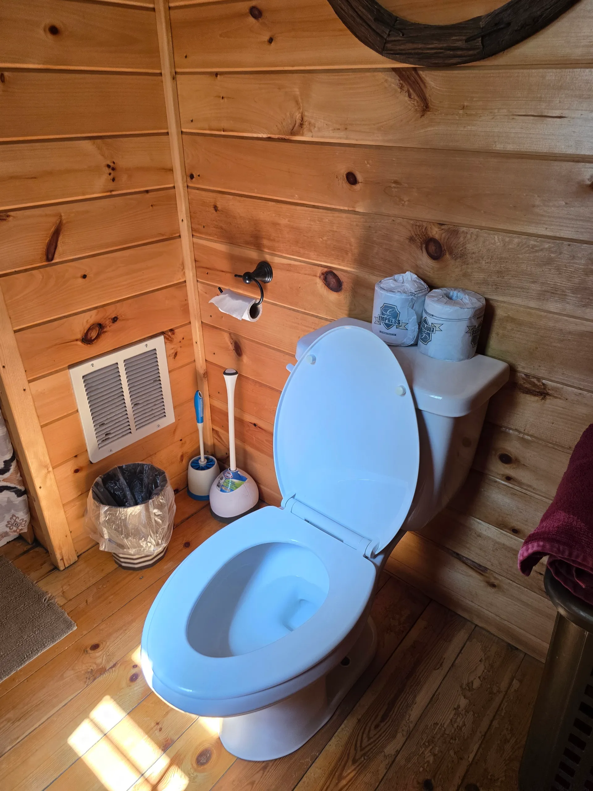 Bathroom with pine-paneled walls and hardwood floor in Settlers Roost cabin