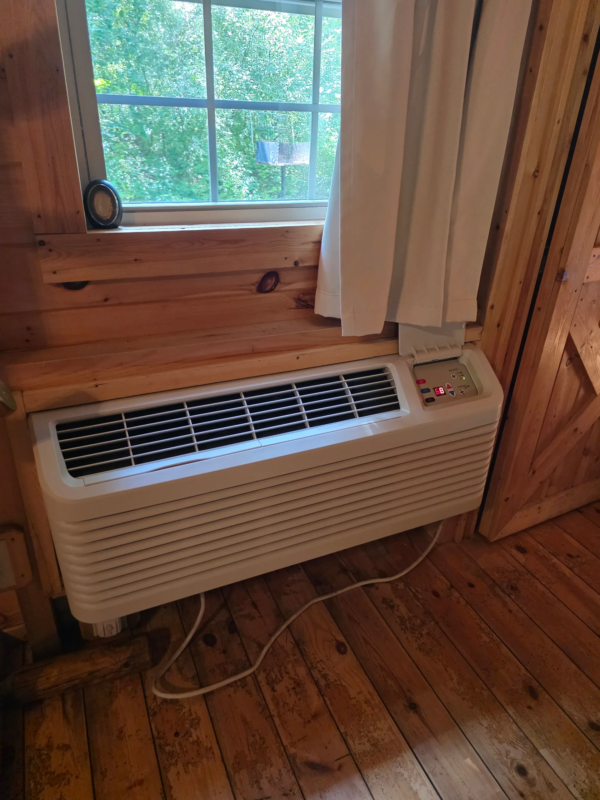 Bedroom window with air conditioning unit providing climate control in Settlers Roost cabin