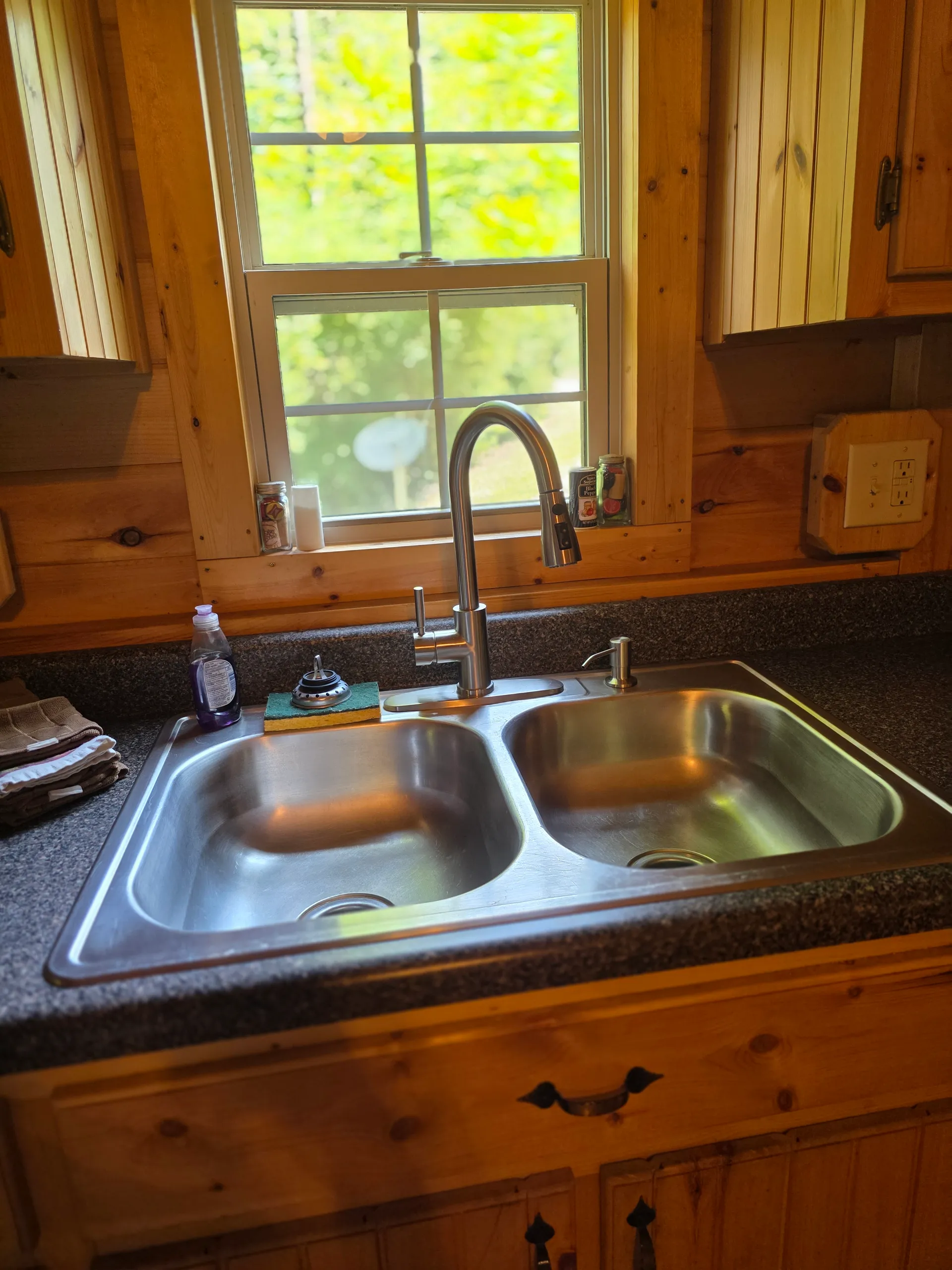 Stainless steel double sink with window overlooking the forest inside Settlers Roost cabin kitchen