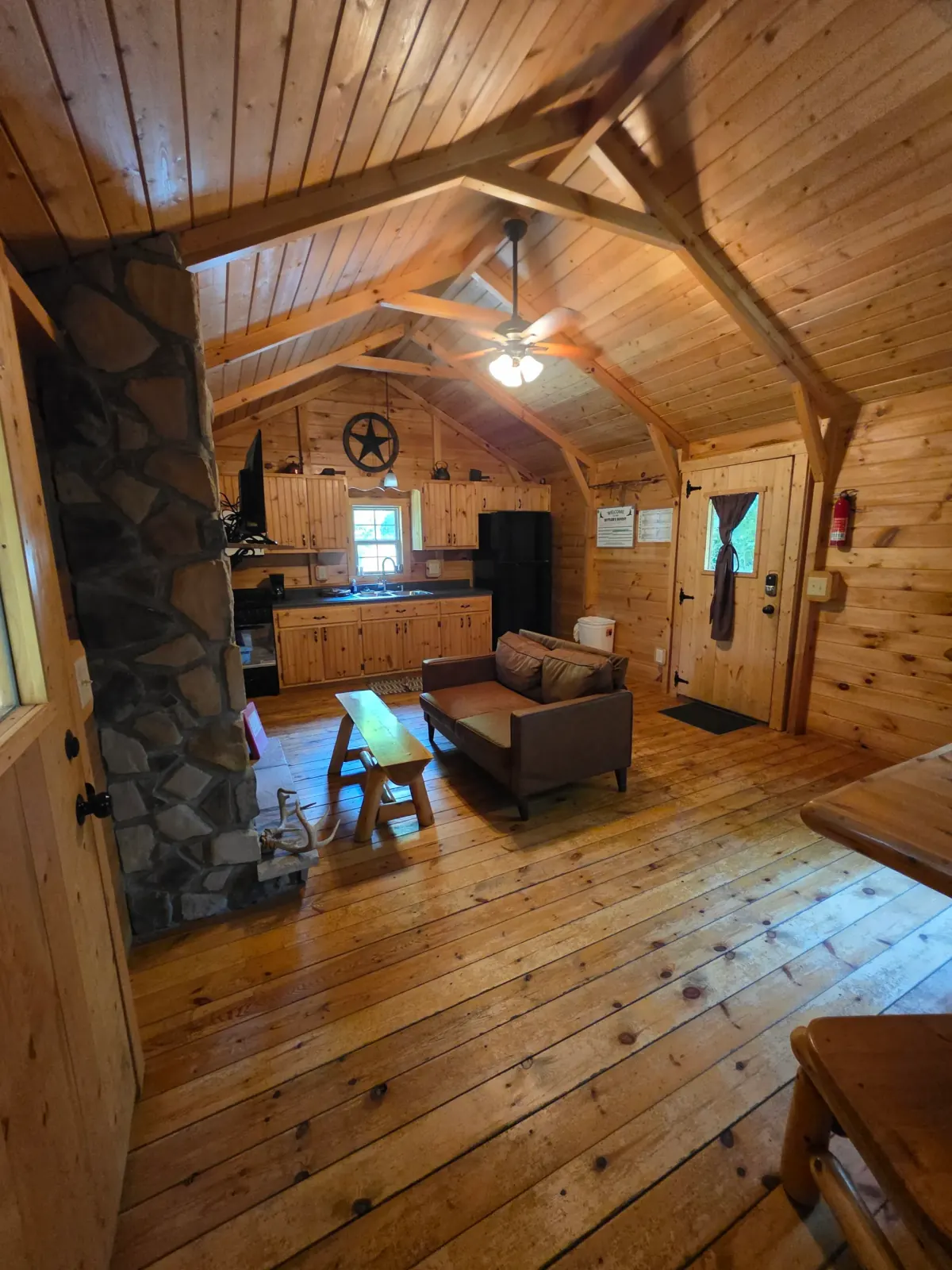 Panoramic loft view of the full interior of Settlers Roost cabin showing kitchen, fireplace, and vaulted ceilings