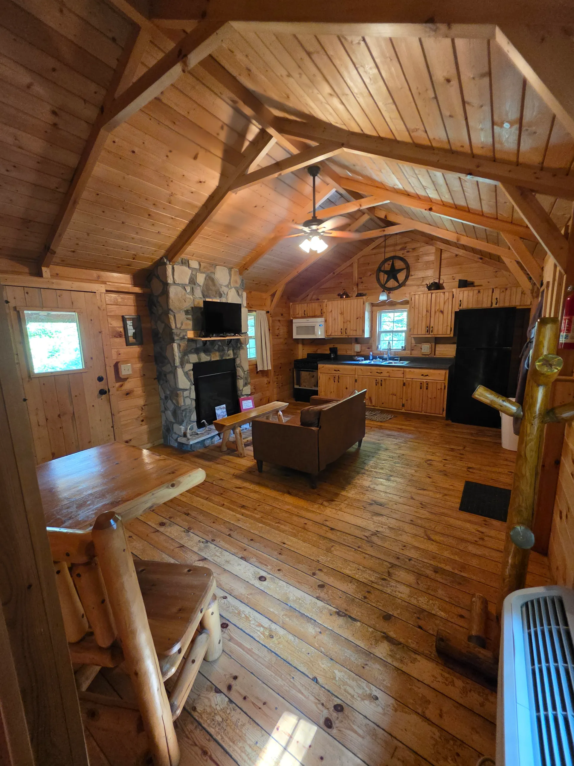 View from the loft overlooking the living room, stone fireplace, and kitchen of Settlers Roost cabin