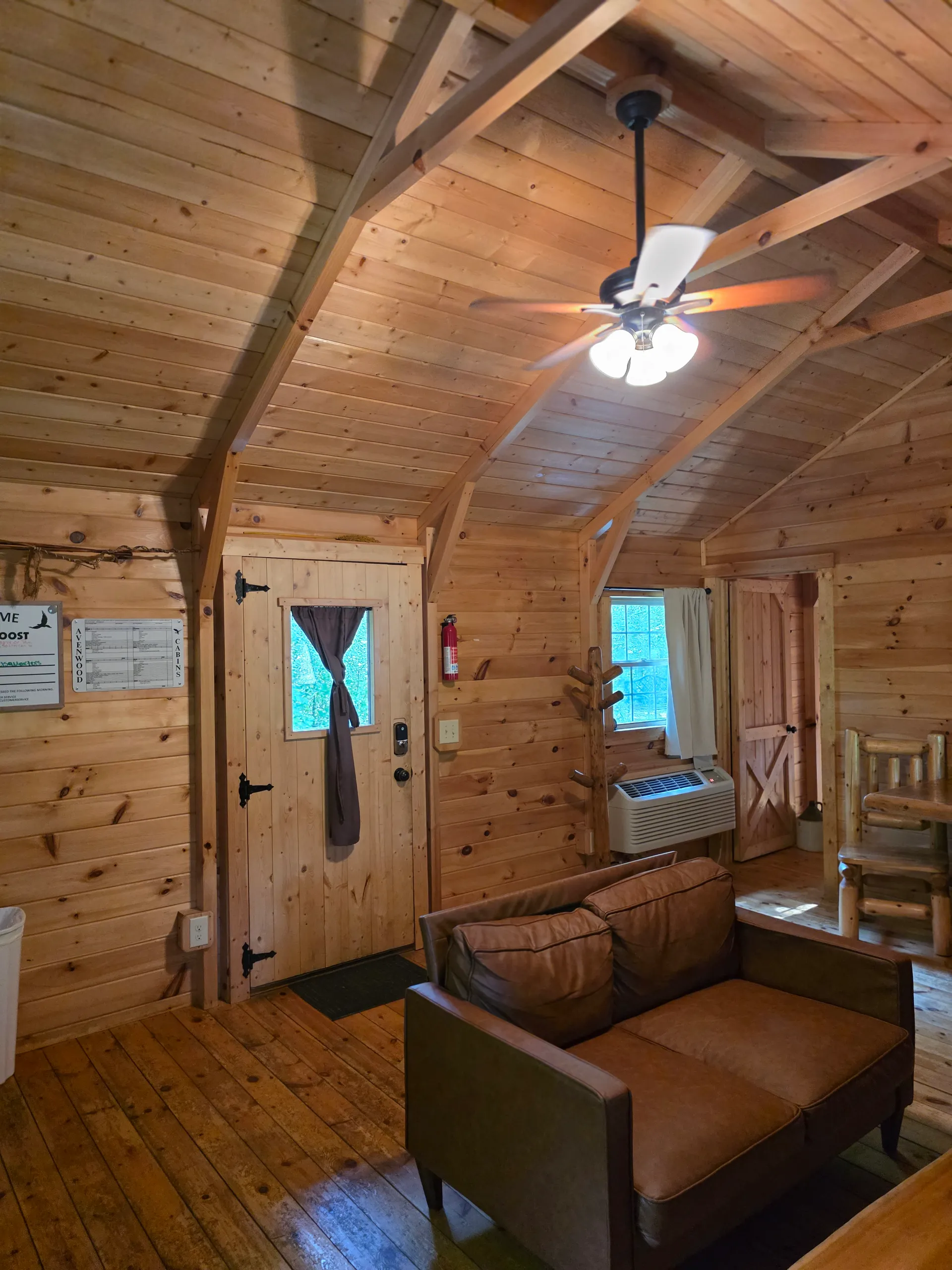 Vaulted pine ceiling with loft railing viewed from below inside Settlers Roost cabin