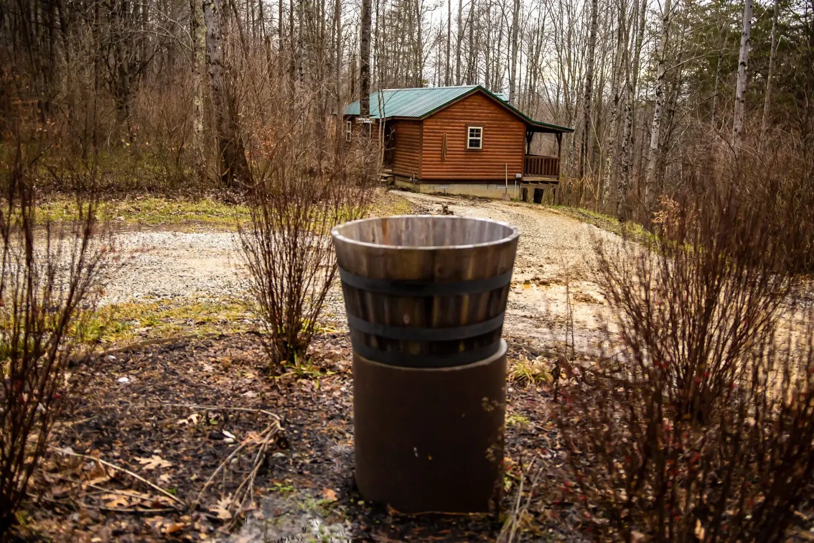 Settlers Roost cabin in winter with bare trees, barrel planter at the entrance, and gravel path in Hocking Hills