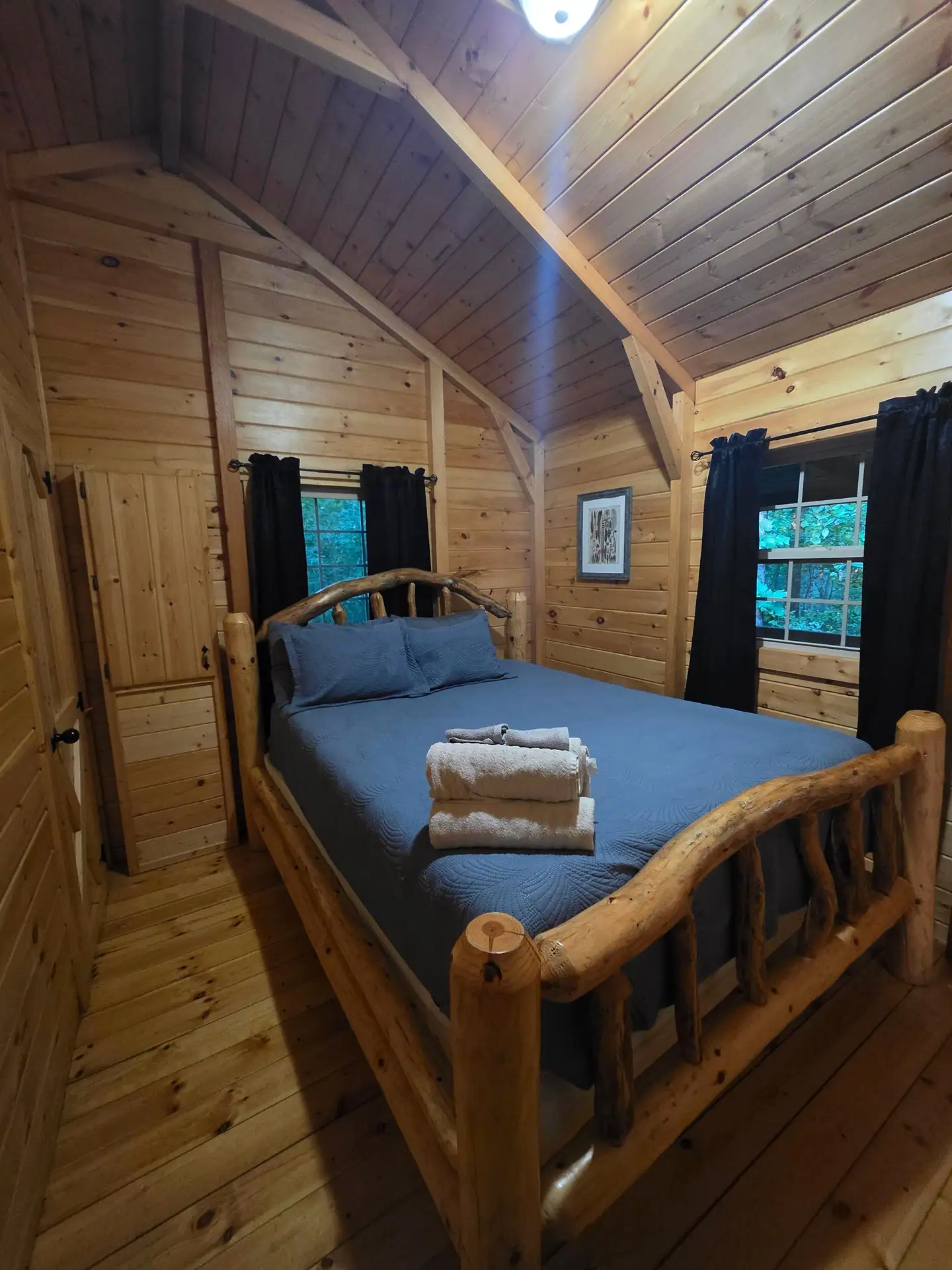 Queen log bed with blue bedding and fresh towels in the Whippoorwill bedroom