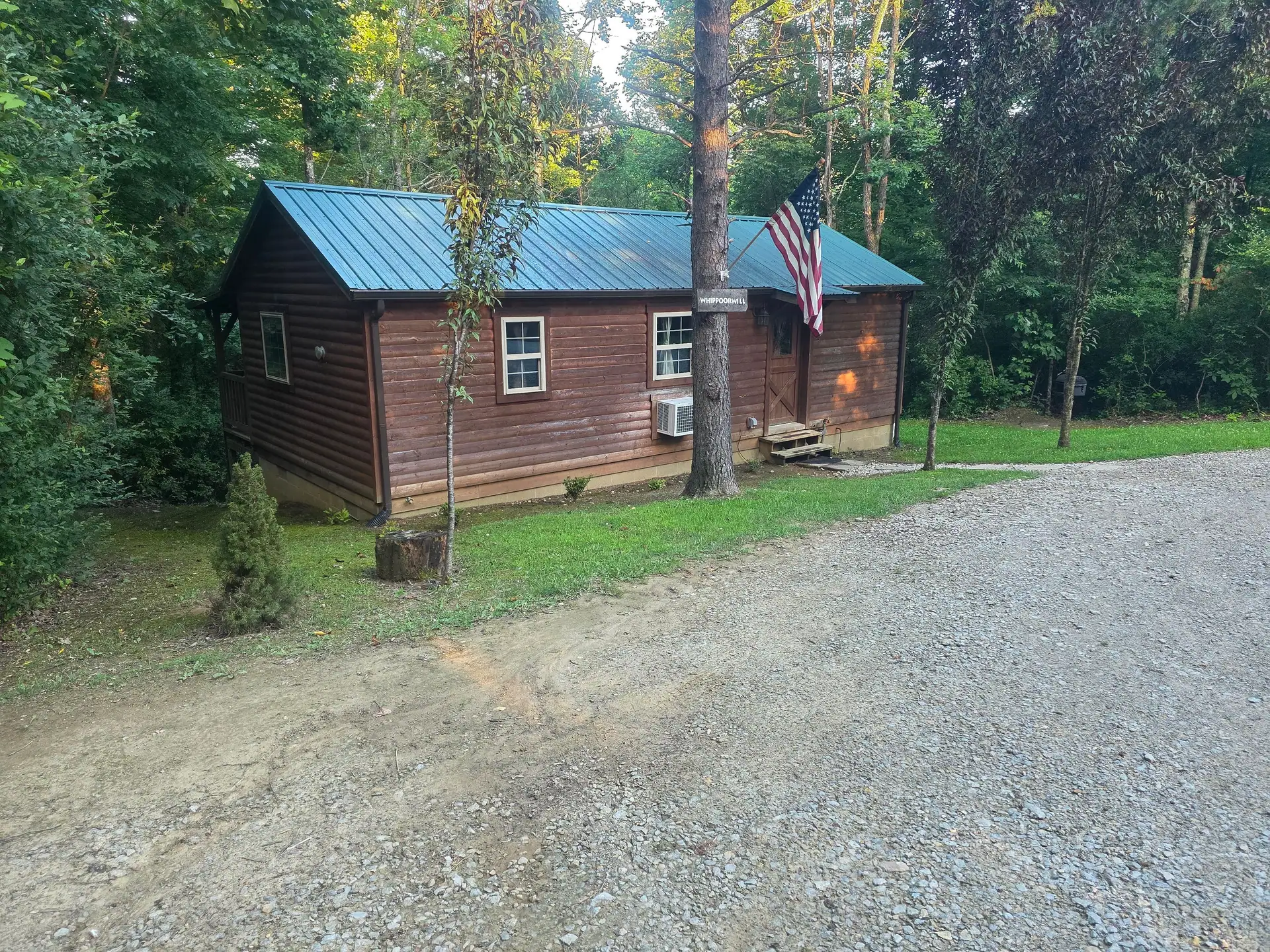 Whippoorwill cabin seen from the gravel driveway among mature trees