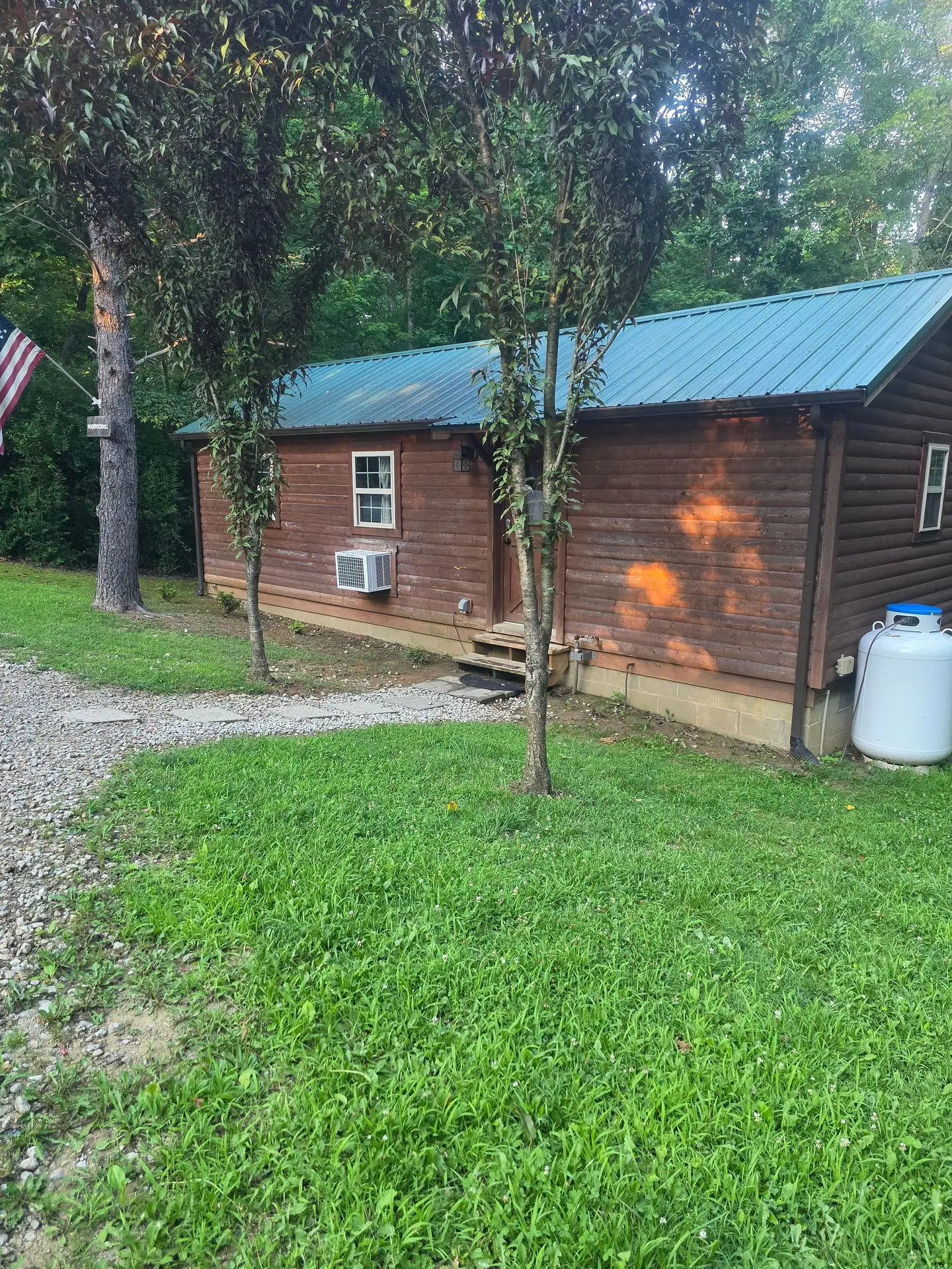Side view of Whippoorwill cabin with its lawn and the woods behind