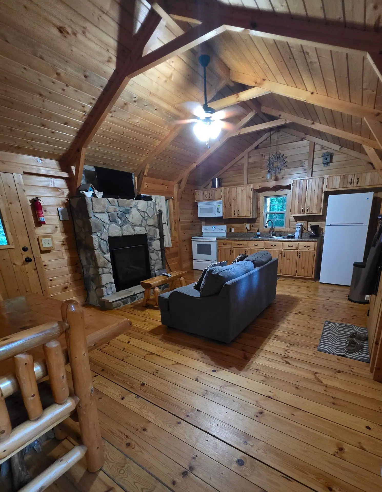 Open living room and kitchen under a vaulted pine ceiling at Whippoorwill