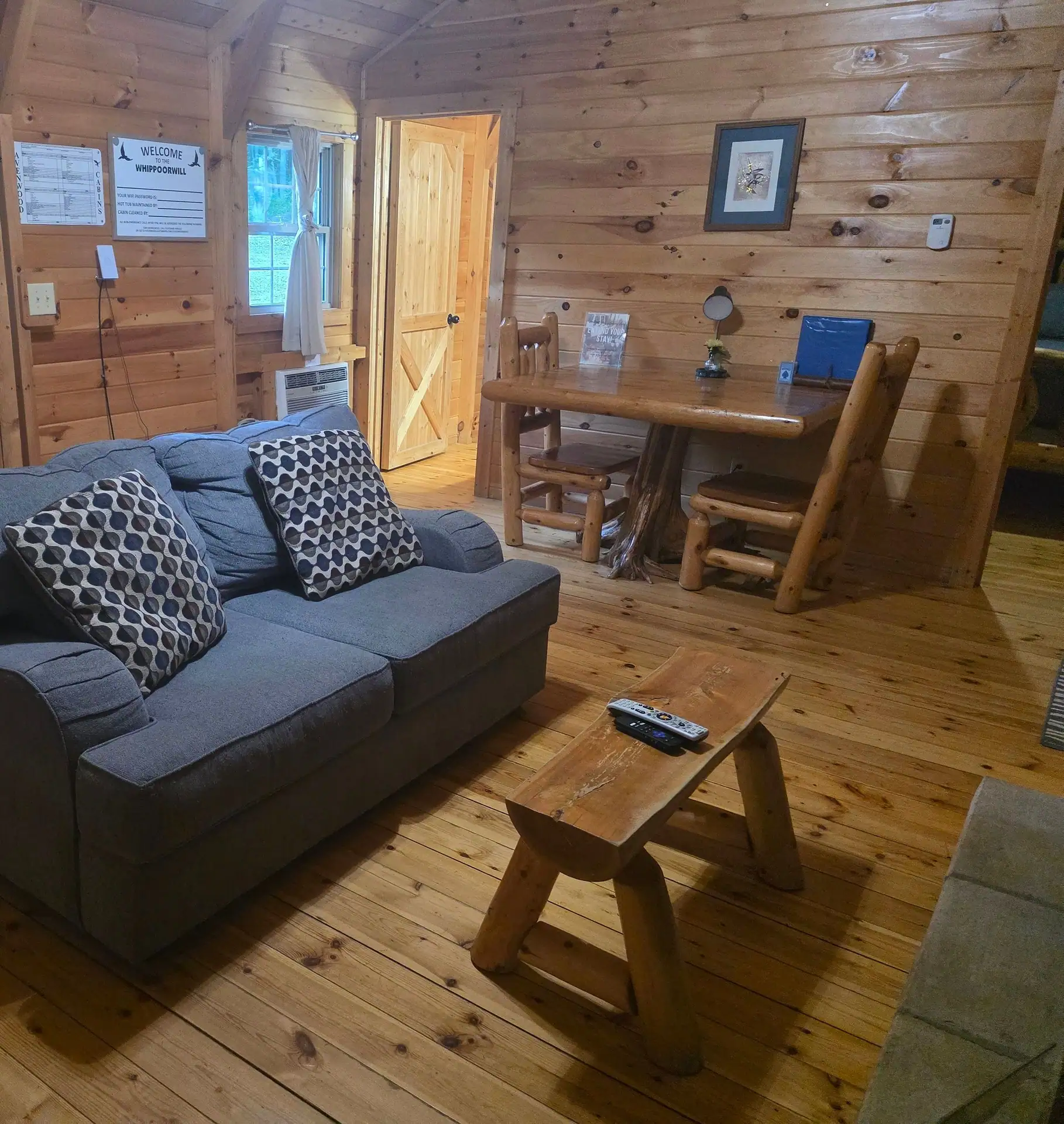 Gray sofa and log dining table in the pine-paneled Whippoorwill living area