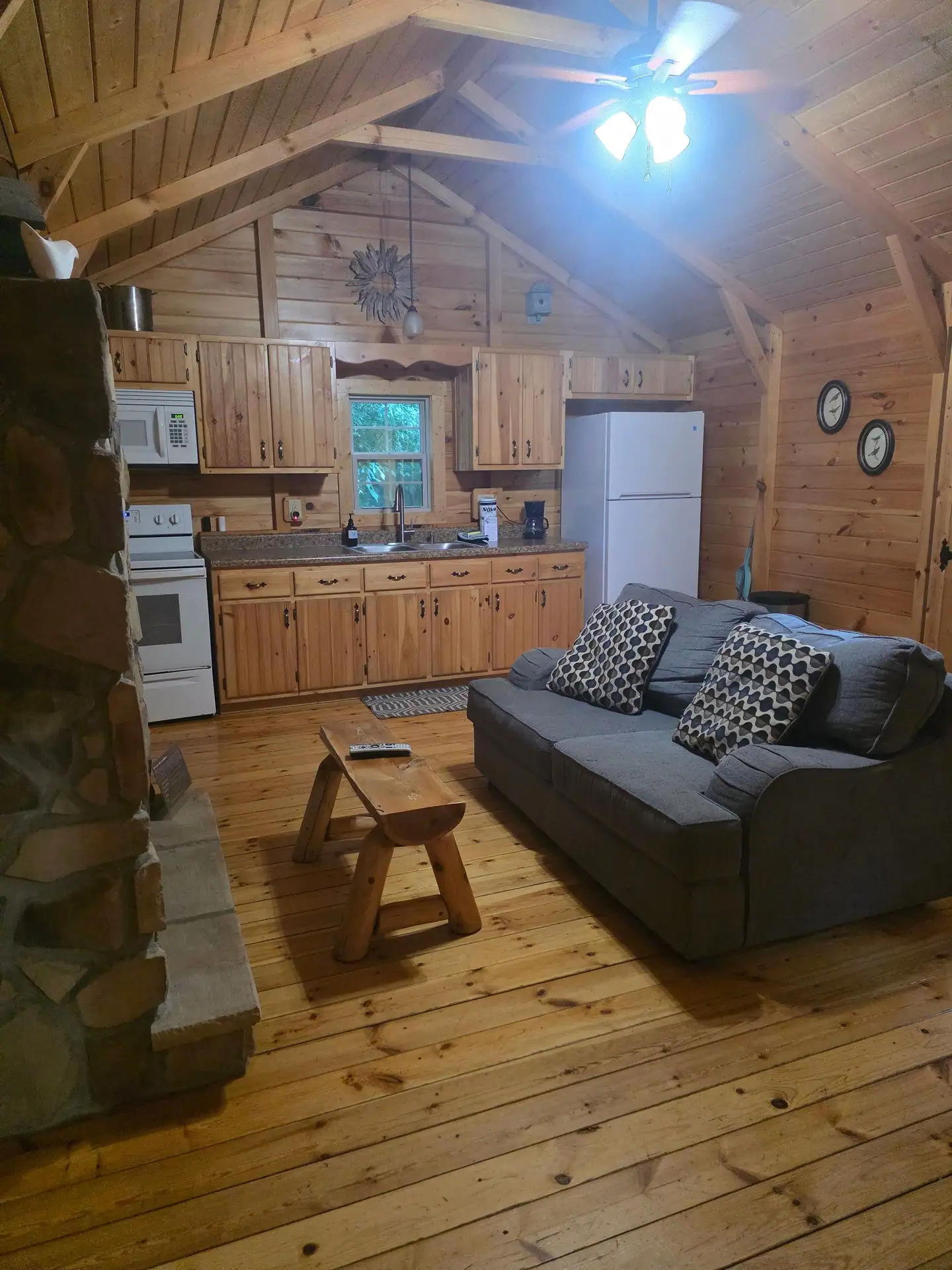 Gray sofa and log coffee table with the kitchen behind in Whippoorwill